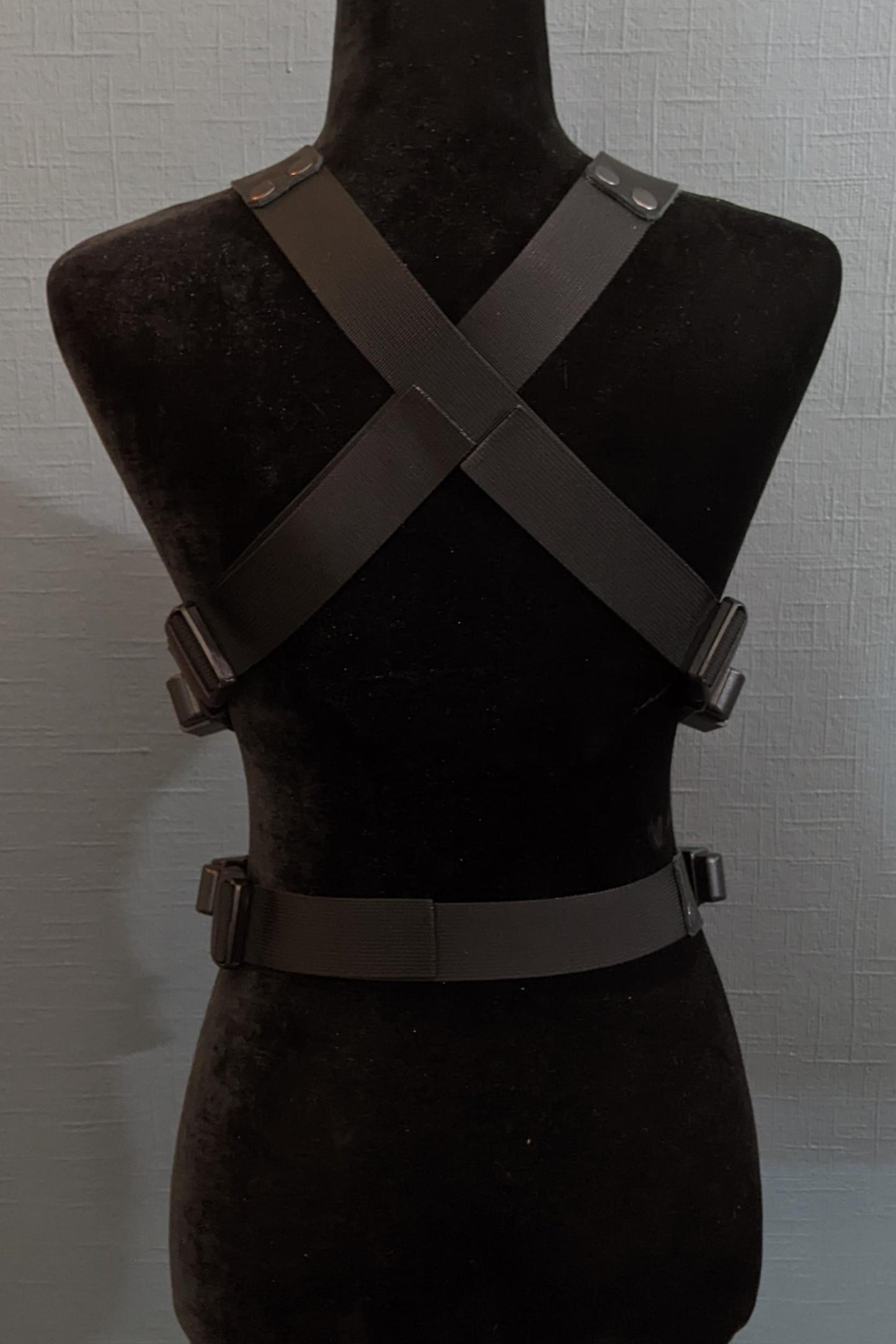 Mannequin wearing futuristic torso armor in black and grey with glowing red lights