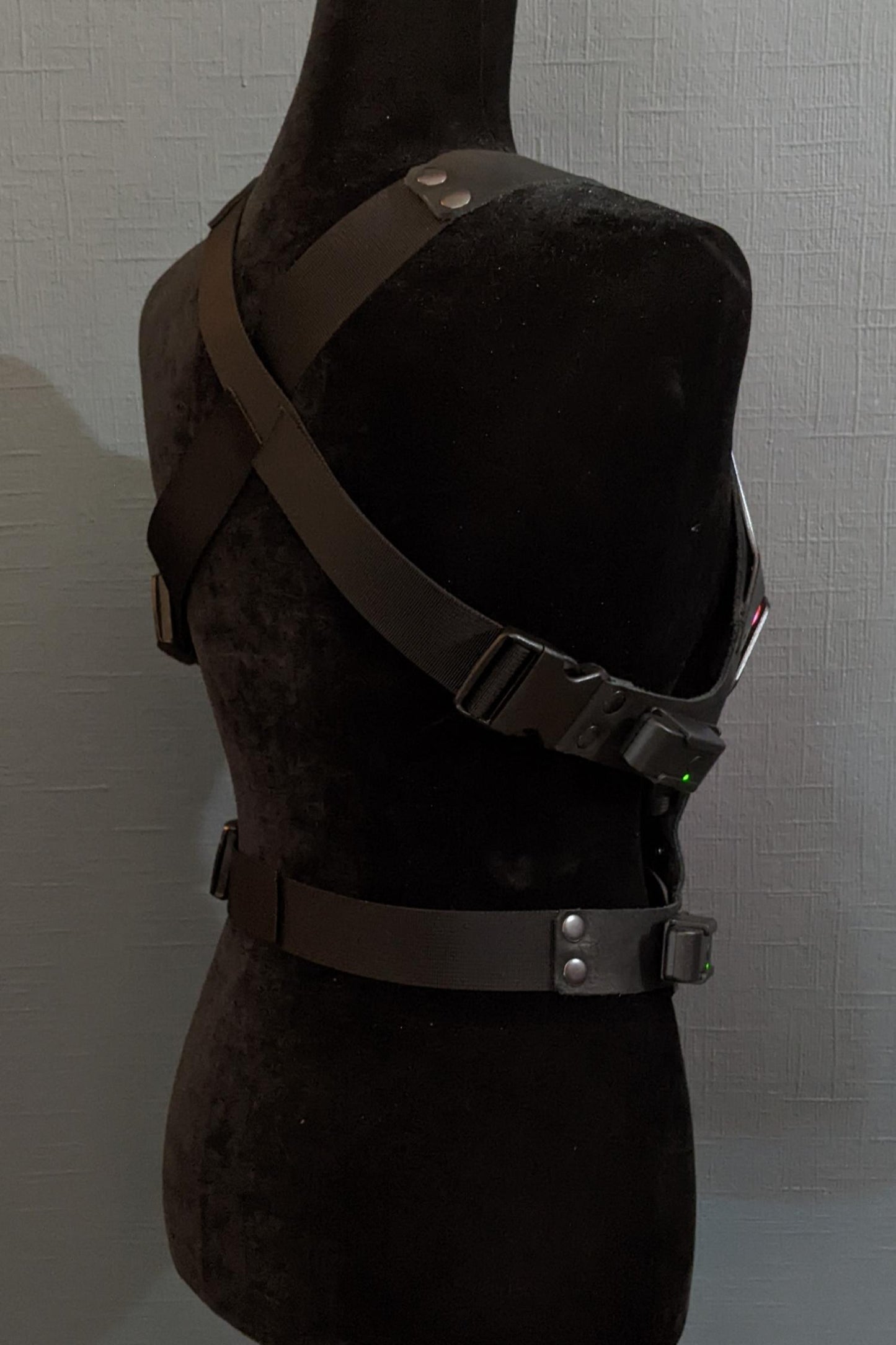 Mannequin wearing futuristic torso armor in black and grey with glowing red lights