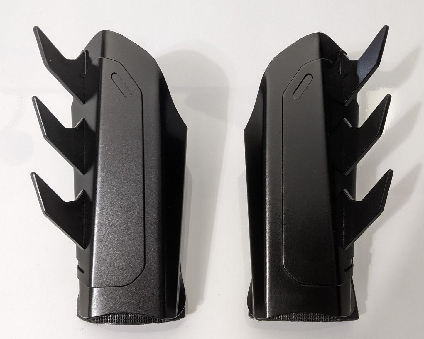 A pair of matte black metal batman arm guards or bracers with angular spikes, displayed side-by-side on a plain white background.