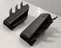 A pair of black protective metal batman guard covers with sharp upward and side spikes, displayed on a clean white surface.