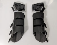 A pair of matte black protective armor metal batman bracers displayed on a clean white surface with a light gray background.