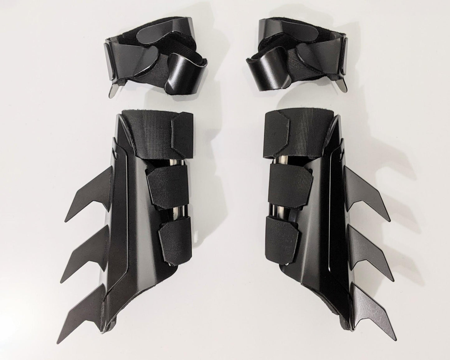 A pair of matte black protective armor metal batman bracers displayed on a clean white surface with a light gray background.