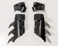 A pair of matte black protective armor metal batman bracers displayed on a clean white surface with a light gray background.