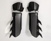 A pair of matte black protective armor metal batman bracers displayed on a clean white surface with a light gray background.